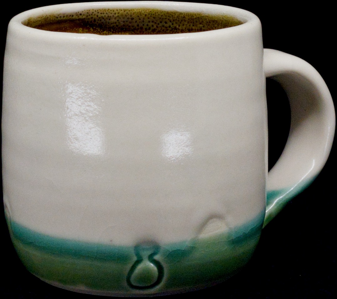 a white mug with an accent of green oribe glaze on the bottom.